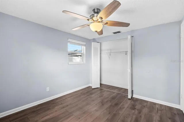 an empty room with wooden floor and ceiling fan