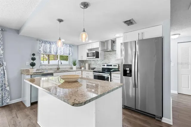 a kitchen with stainless steel appliances granite countertop a refrigerator a sink a stove a microwave and island