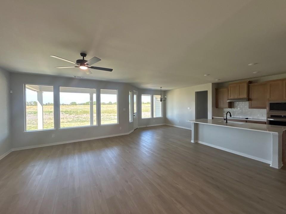 8685 County Road 623 Blue Ridge, TX 75424 - Photo 4 of 12 Wood-finish flooring throughout, with a multi-pane window wall, ceiling fan, and kitchen island featuring a sink and black faucet