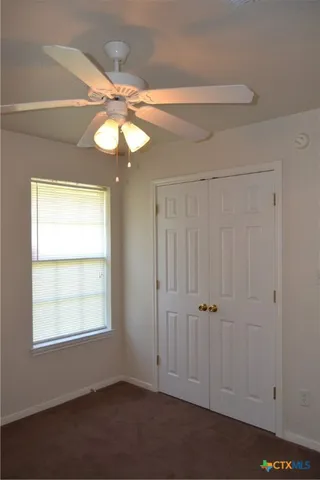 an empty room with windows and chandelier fan