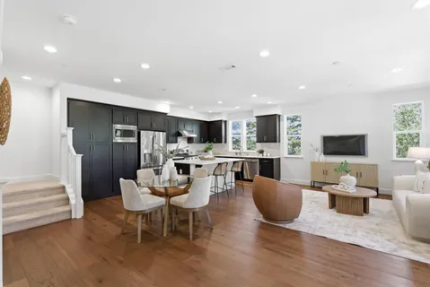a living room with furniture a flat screen tv and kitchen view