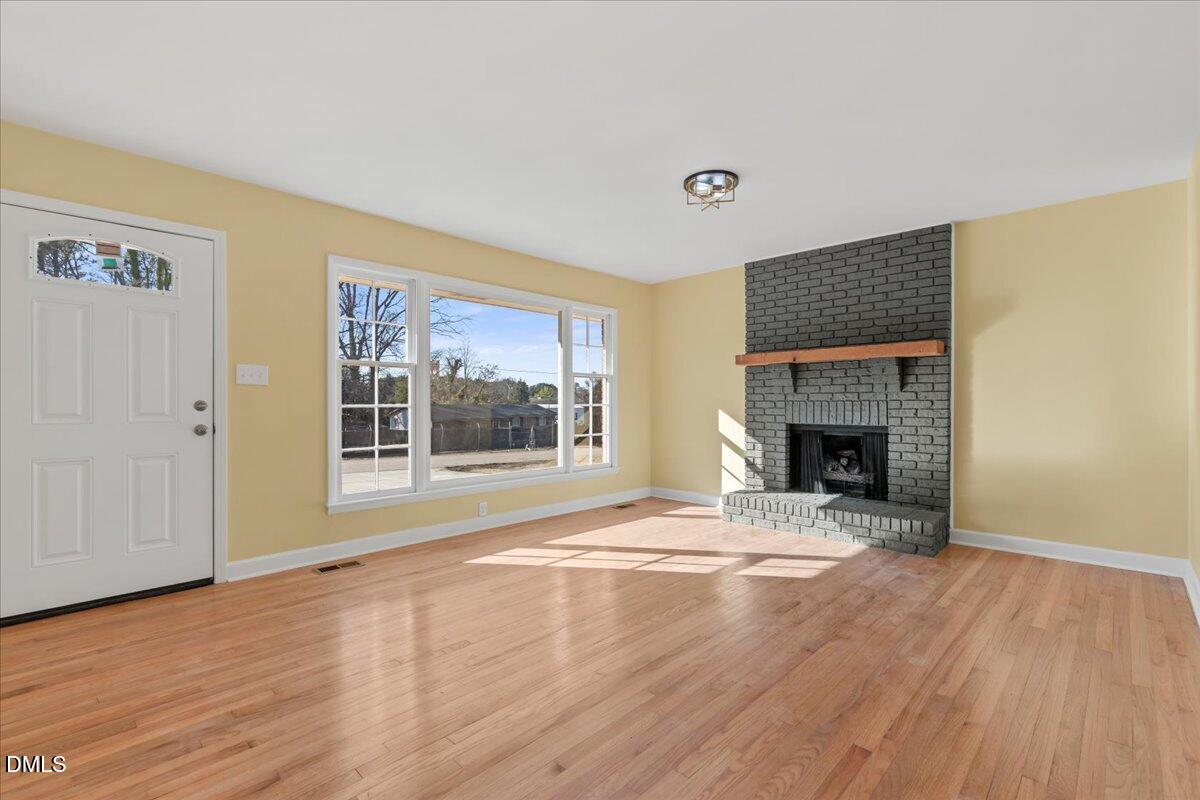 3620 Oates Drive Raleigh, NC 27604 - Photo 5 of 26 a view of empty room with wooden floor and fireplace