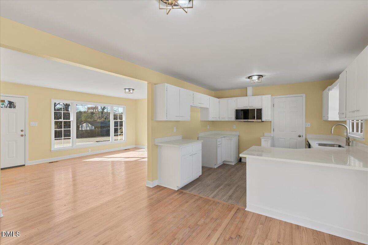 3620 Oates Drive Raleigh, NC 27604 - Photo 8 of 26 a large white kitchen with white cabinets and wooden floor