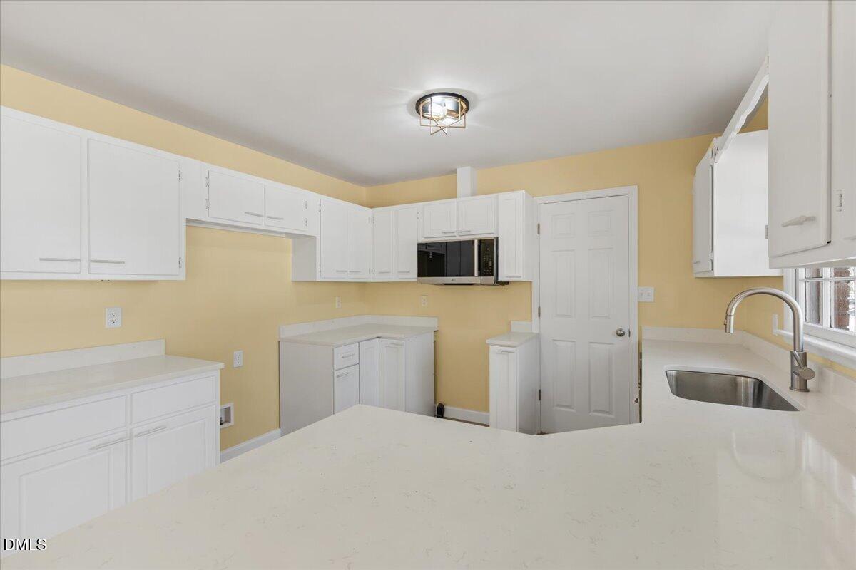 3620 Oates Drive Raleigh, NC 27604 - Photo 10 of 26 a kitchen with a refrigerator sink and white cabinets