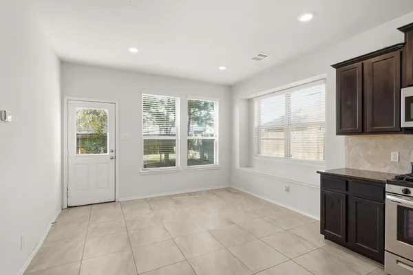 a view of an empty room with a window and a kitchen