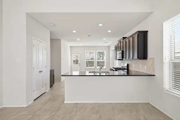 a large white kitchen with granite countertop a sink and dishwasher a granite counter top