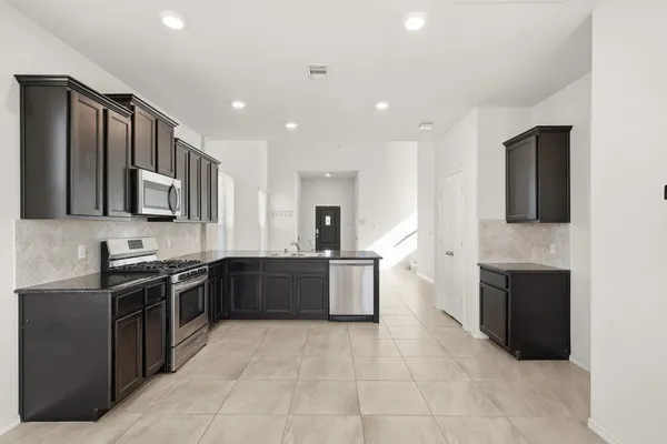 a large kitchen with stainless steel appliances granite countertop a stove top oven a sink dishwasher a refrigerator and a microwave oven on the blue kitchen countertops