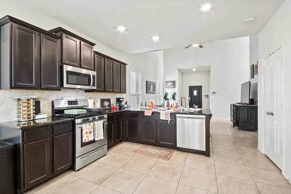 a kitchen with stainless steel appliances granite countertop a stove top oven a sink dishwasher and a refrigerator