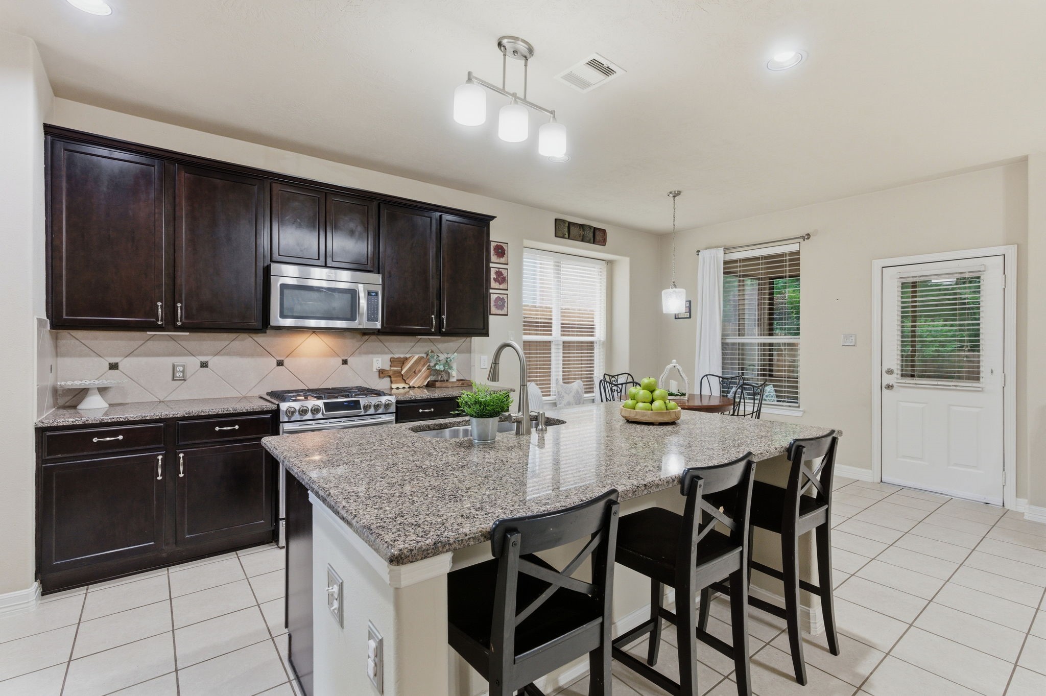 1737 Round Oak Lane Conroe, TX 77304 - Photo 5 of 39 a kitchen with granite countertop wooden cabinets a stove a oven a dining table and chairs