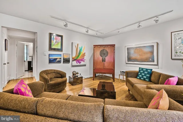a living room with furniture kitchen view and a wooden floor