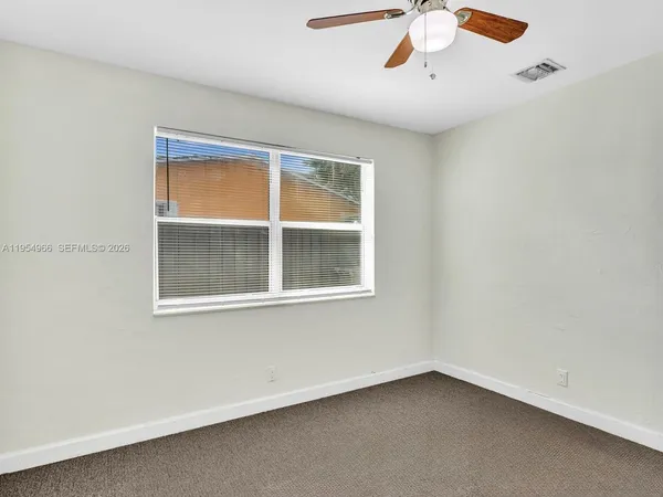an empty room with a window and a fan