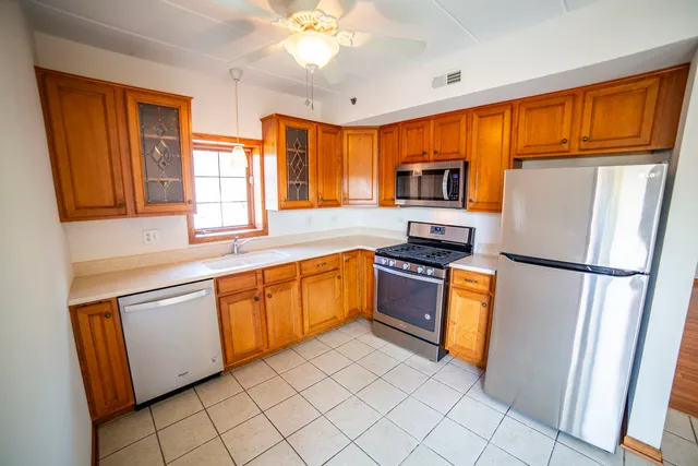 a kitchen with granite countertop stainless steel appliances a refrigerator stove top oven and sink