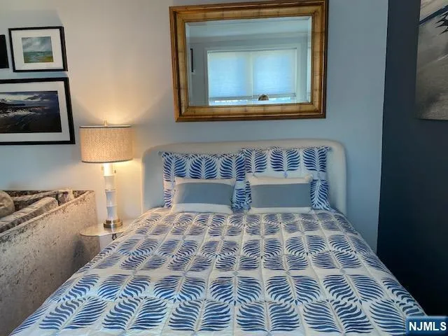 a bedroom with a bed and a lamp on dresser