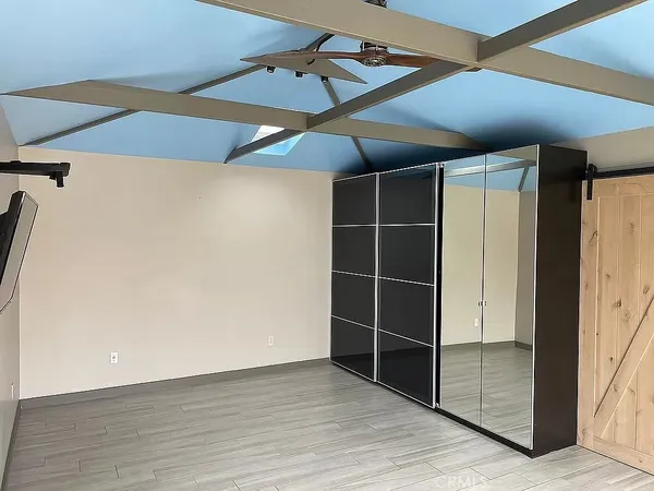 an empty room with wooden floor closet and windows