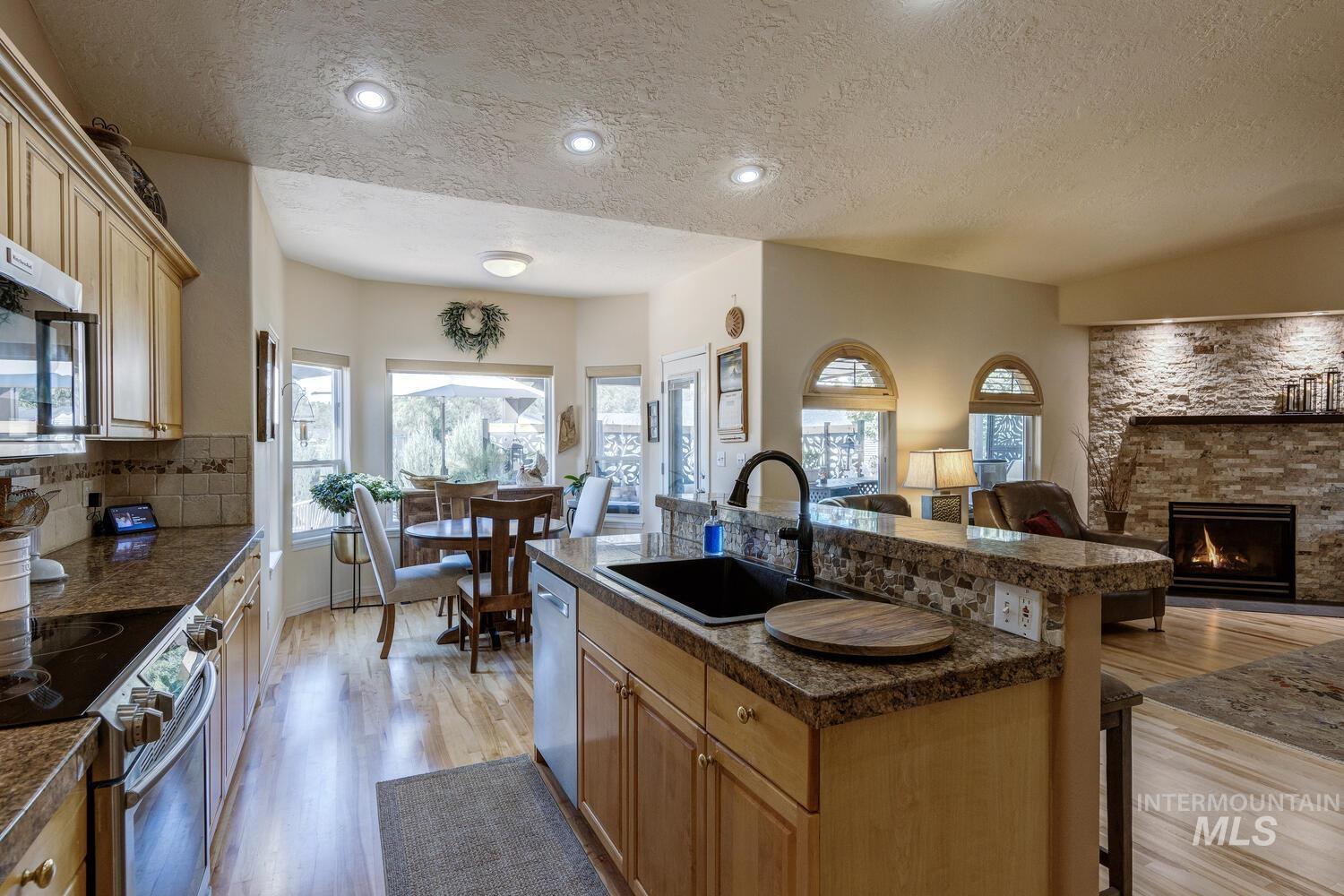 10585 West Vega Court Star, ID 83669 - Photo 13 of 49 Kitchen with an island with sink, a textured ceiling, stainless steel appliances, light wood-style flooring, and a breakfast bar area