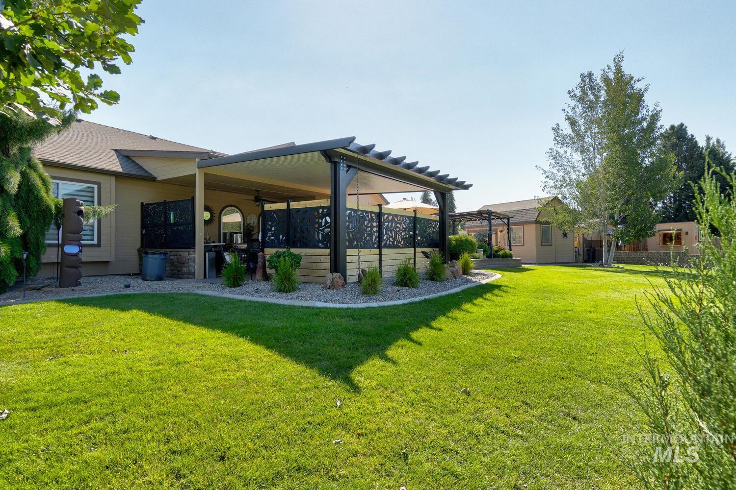 10585 West Vega Court Star, ID 83669 - Photo 43 of 49 Back of house featuring a lawn, a patio, and stone siding