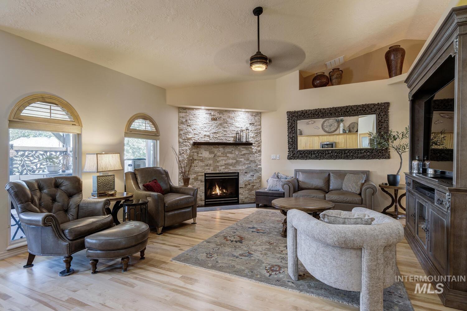 10585 West Vega Court Star, ID 83669 - Photo 7 of 49 Living area featuring vaulted ceiling, a fireplace, light wood finished floors, a ceiling fan, and a textured ceiling