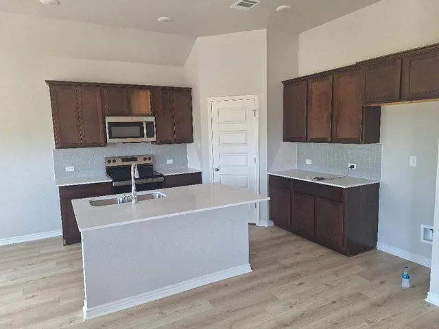 a kitchen with kitchen island a counter top space appliances and cabinets