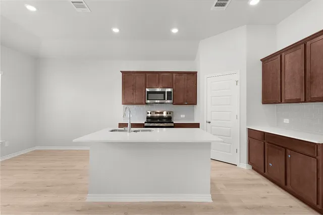 a kitchen with stainless steel appliances granite countertop a stove a sink and a microwave