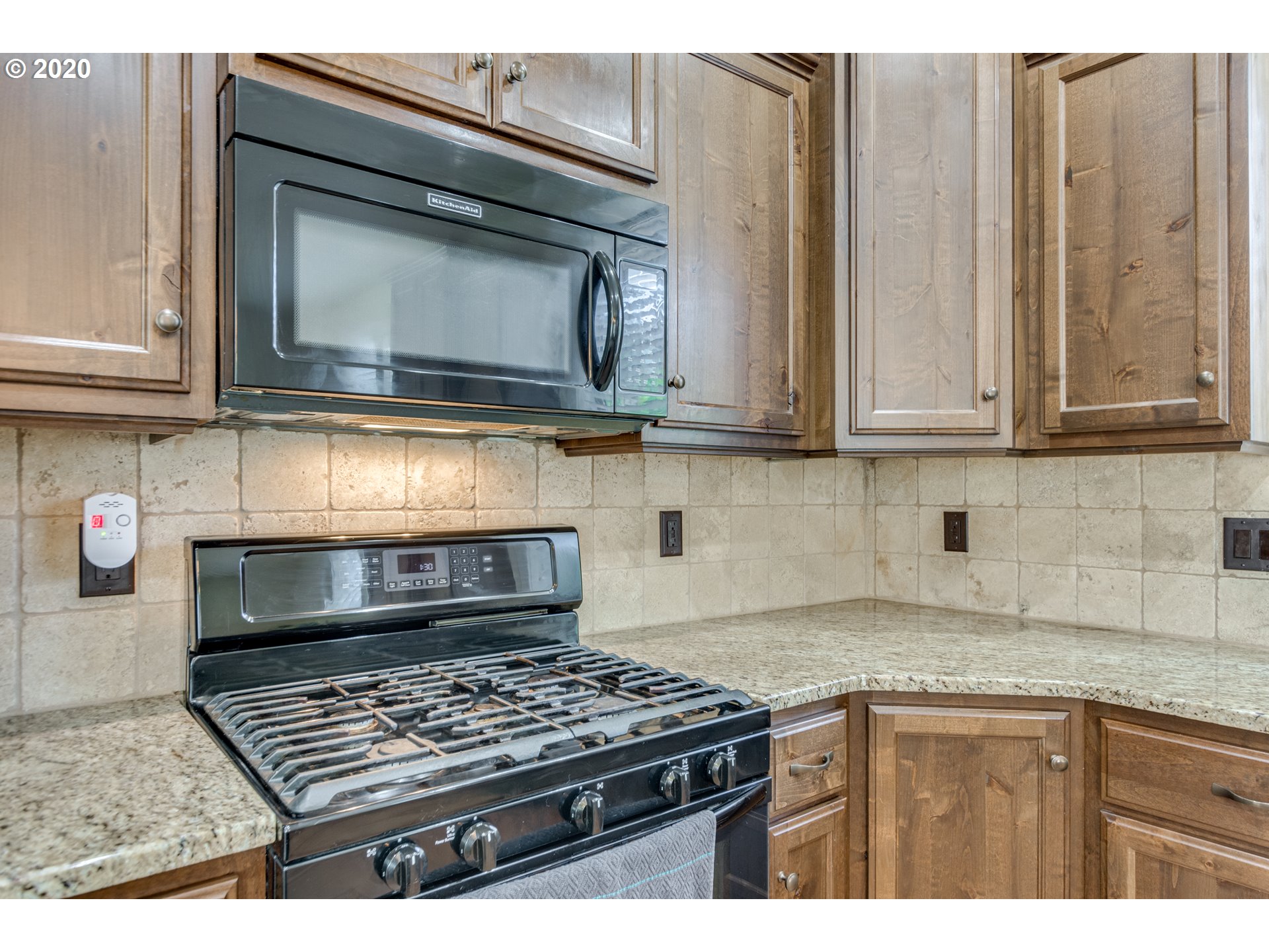 4009 North 5th Way Ridgefield, WA 98642 - Photo 10 of 32 a kitchen with granite countertop a stove top oven cabinetry a chimney and garage