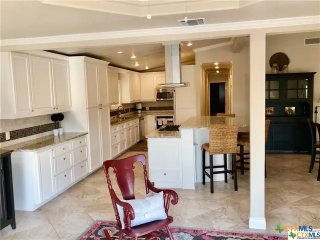 a kitchen with stainless steel appliances kitchen island granite countertop a table and chairs in it