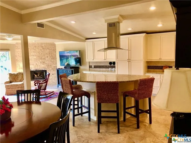 a dining room with kitchen island a table chairs and a refrigerator
