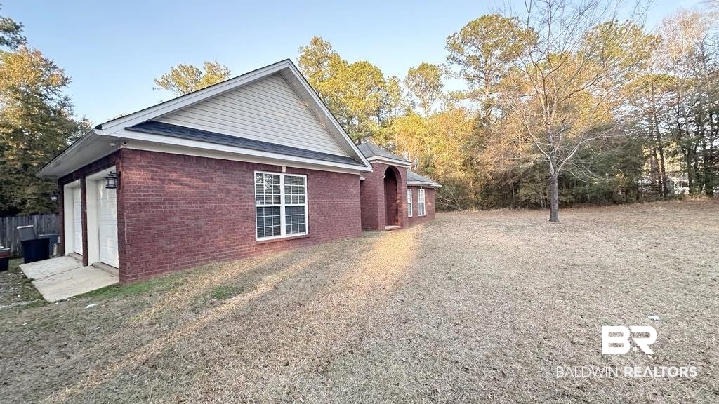 23289 McPhillips Road Loxley, AL 36551 - Photo 14 of 19 Brick exterior with white trim, featuring a gable roof and an attached two-car garage