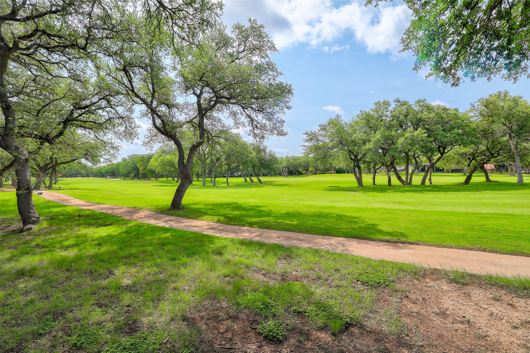 33 Meadows End Georgetown, TX 78628 - Photo 39 of 40 A verdant golf course stretches under a clear sky, bordered by a walking path and mature trees.
