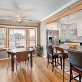 a dining hall with stainless steel appliances granite countertop a stove a kitchen island a table and chairs