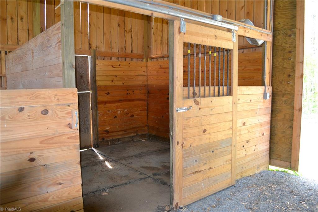 1484 Smothers Road Madison, NC 27025 - Photo 7 of 30 The barn is currently configured with 2 very large stalls, and an oversized run in area. Additional stalls could easily be added. Across the passageway is an equipment storage area and large hay loft that runs the length of the barn (not shown). Note extra large barn door to the right of the stall.