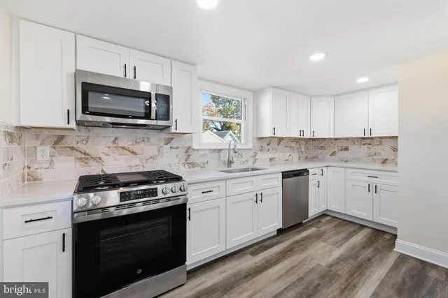 a kitchen with granite countertop a stove a sink and a microwave