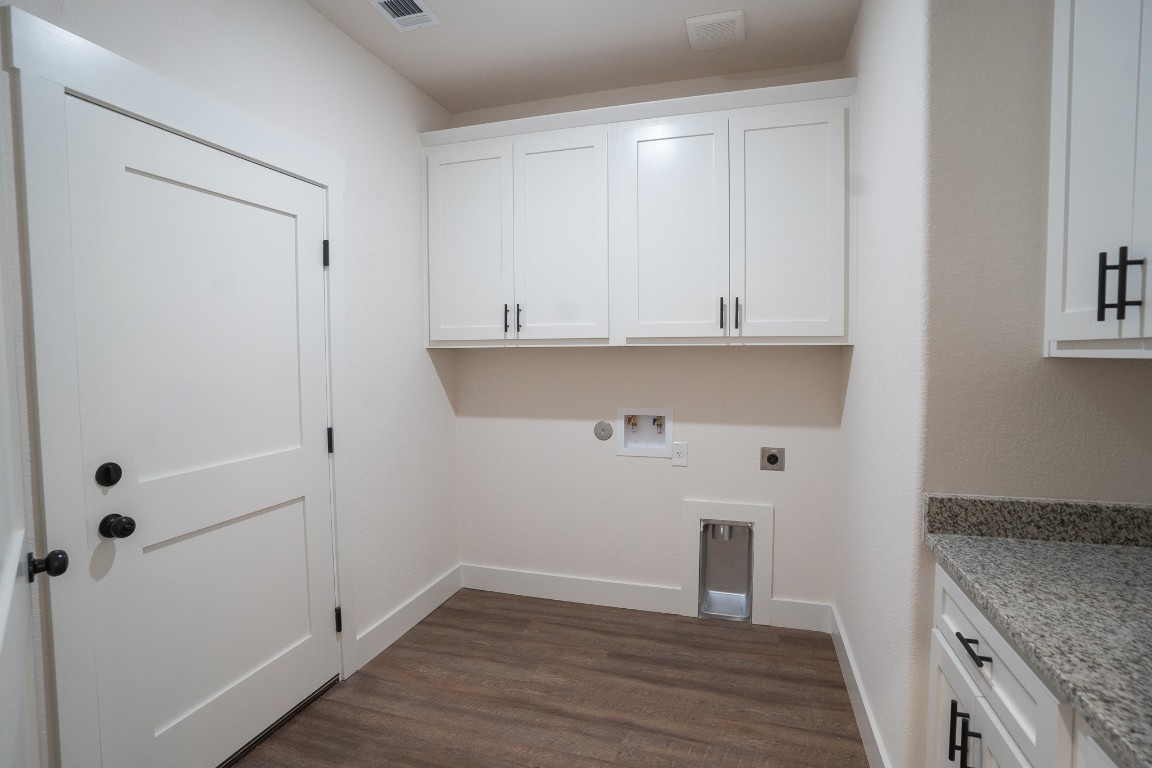 304 String Prairie Way Smithville, TX 78957 - Photo 29 of 30 Laundry area with cabinet space, electric dryer hookup, hookup for a washing machine, dark wood-style flooring, and baseboards
