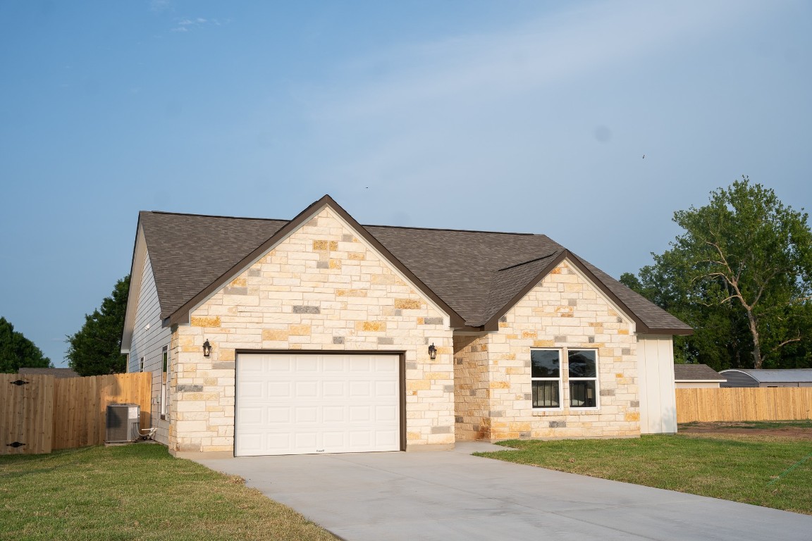 304 String Prairie Way Smithville, TX 78957 - Photo 3 of 30 French country inspired facade with roof with shingles, a garage, concrete driveway, and stone siding