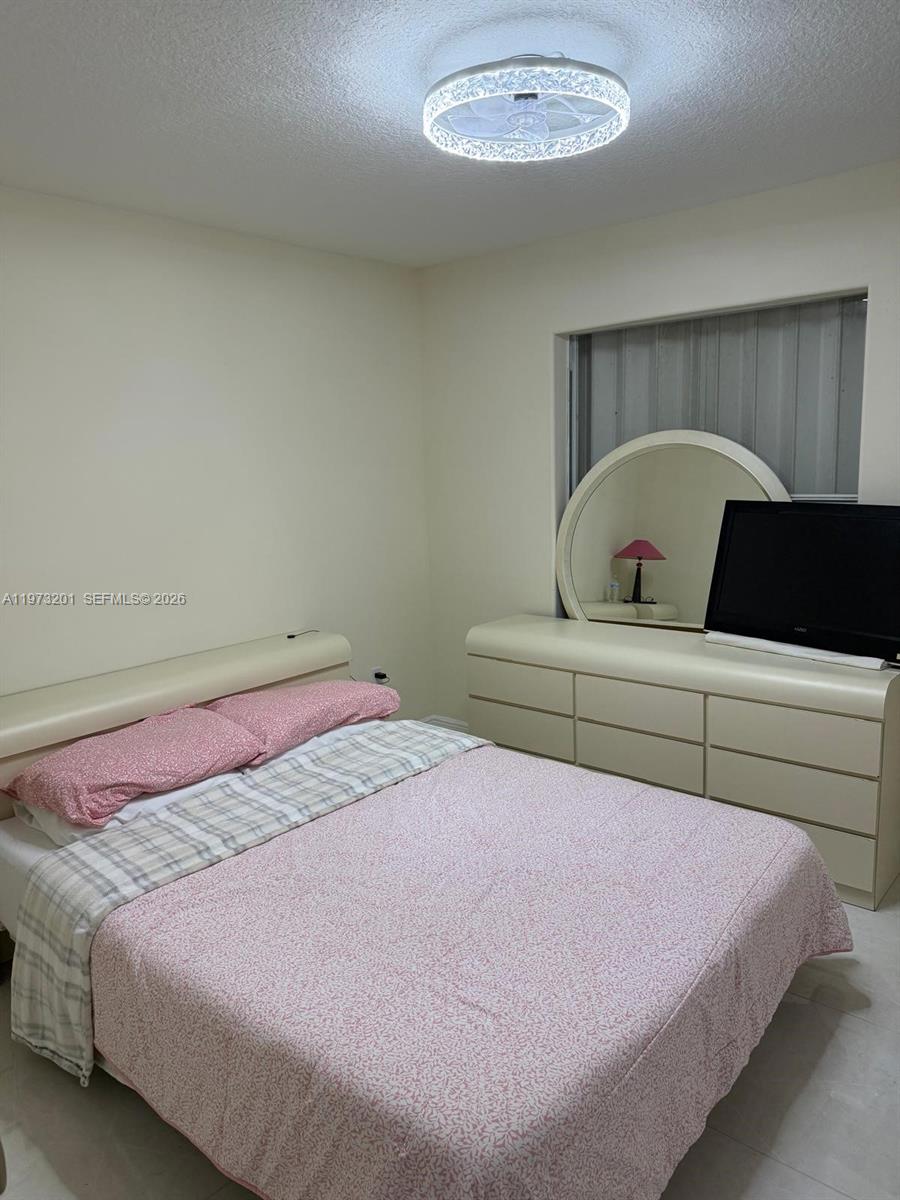 28565 Southwest 158th Court, Unit A Homestead, FL 33033 - Photo 9 of 11 a bedroom with a bed and a chandelier
