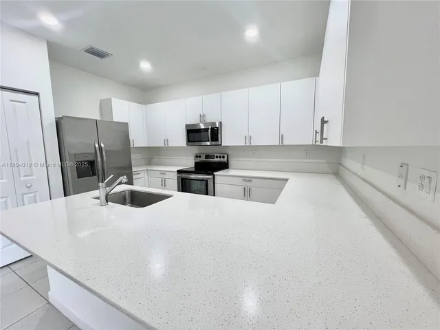 a kitchen with stainless steel appliances a refrigerator sink stove microwave and cabinets