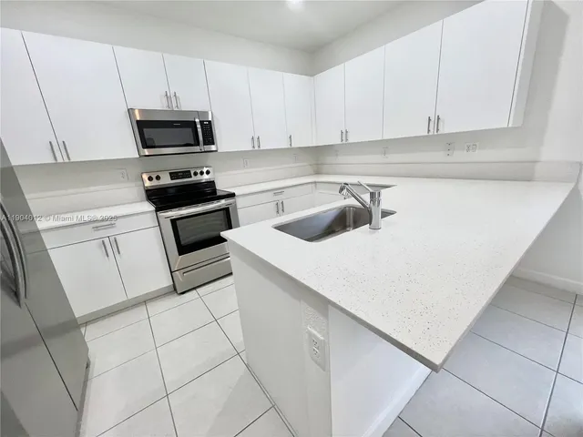 a kitchen with white cabinets a sink and white appliances
