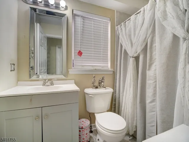 a bathroom with a sink a toilet a mirror and shower curtain