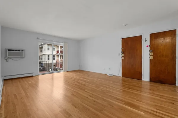 a view of an empty room with wooden floor and a window