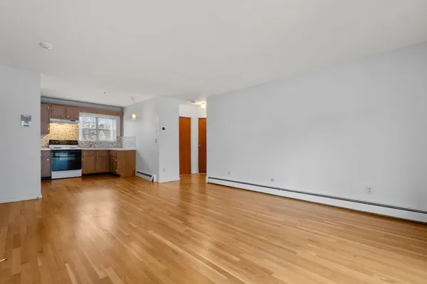 a view of an empty room with wooden floor and a cabinet