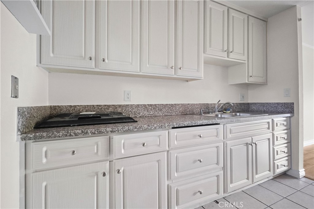 11311 Tampa Avenue, Unit 21 Porter Ranch, CA 91326 - Photo 12 of 36 a kitchen with granite countertop white cabinets and a sink