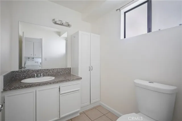 a bathroom with a granite countertop sink a mirror and a toilet