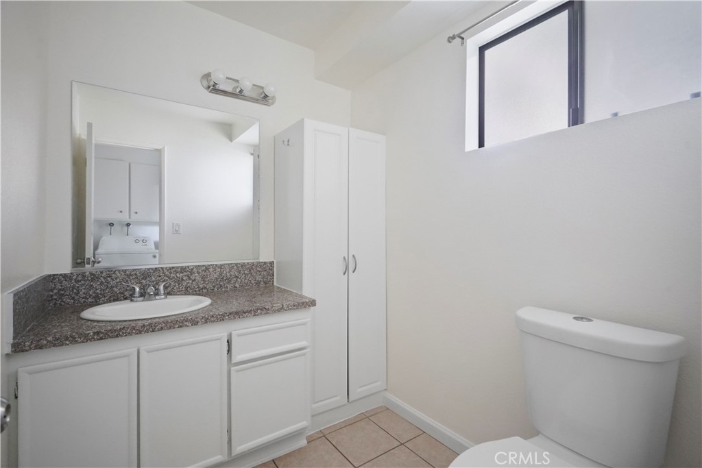 11311 Tampa Avenue, Unit 21 Porter Ranch, CA 91326 - Photo 13 of 36 a bathroom with a granite countertop sink a mirror and a toilet