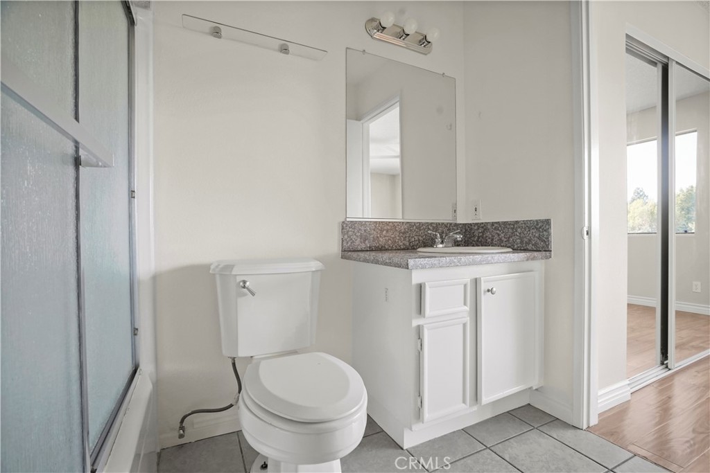 11311 Tampa Avenue, Unit 21 Porter Ranch, CA 91326 - Photo 20 of 36 a bathroom with a granite countertop sink a toilet and a mirror