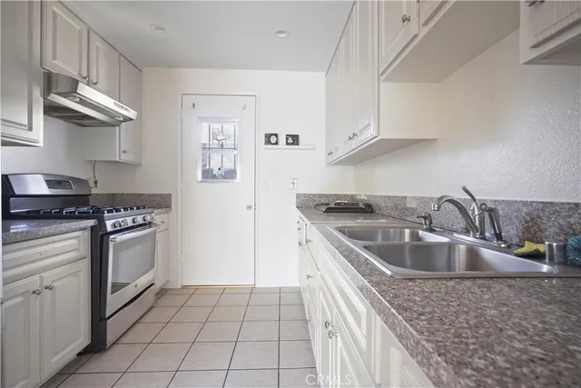 a kitchen with granite countertop a sink stove and cabinets