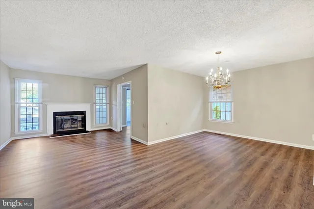 an empty room with wooden floor fire place and windows