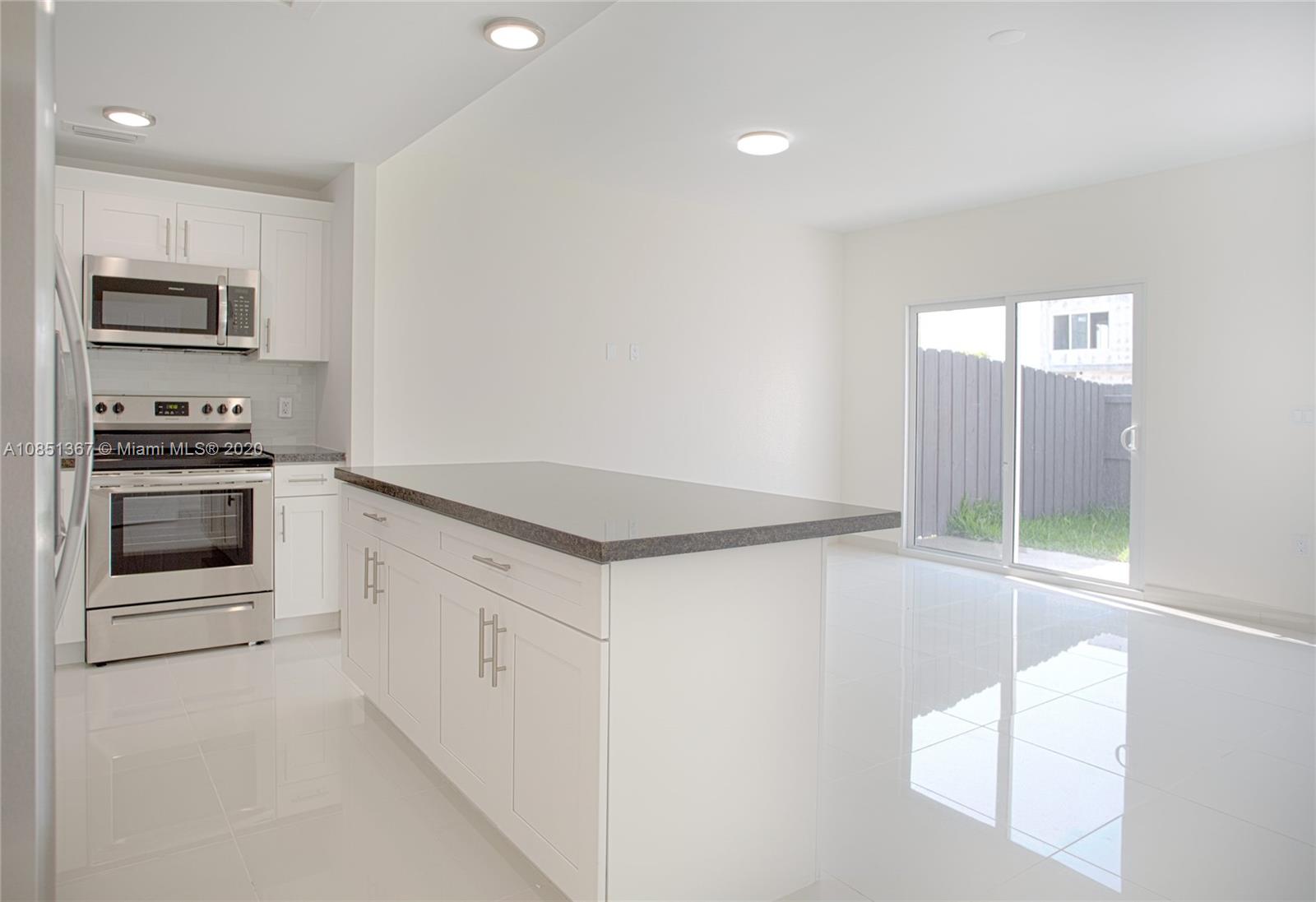 13724 Southwest 259th Street Homestead, FL 33032 - Photo 7 of 20 a kitchen with stainless steel appliances a stove a microwave and white cabinets
