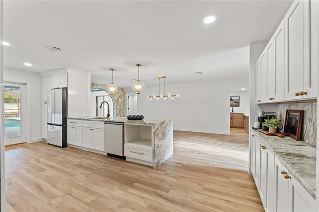 a kitchen with white cabinets and wooden floor