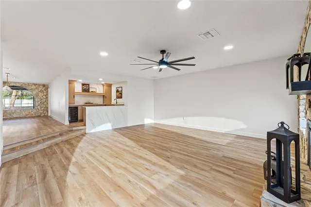 an empty room with wooden floor and ceiling fan