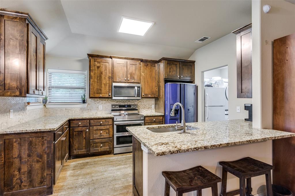 129 Ronnie Lane Weatherford, TX 76088 - Photo 14 of 36 a kitchen with granite countertop kitchen island stainless steel appliances a stove refrigerator sink and cabinets