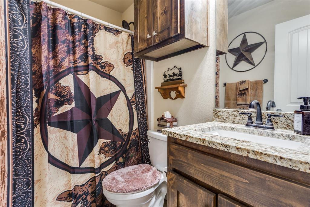 129 Ronnie Lane Weatherford, TX 76088 - Photo 23 of 36 a bathroom with a granite countertop sink a toilet and a mirror